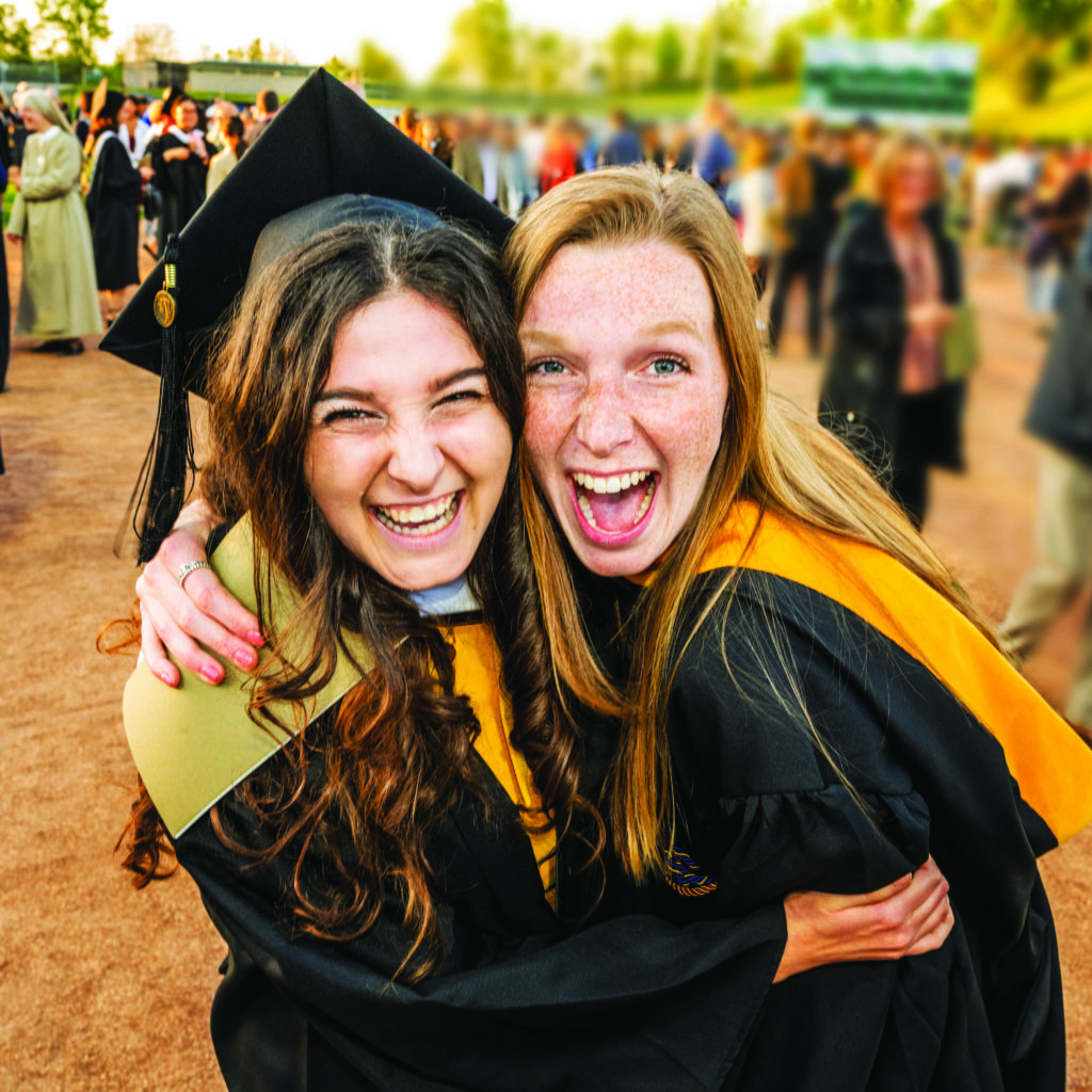 two graduated students happy and hugging