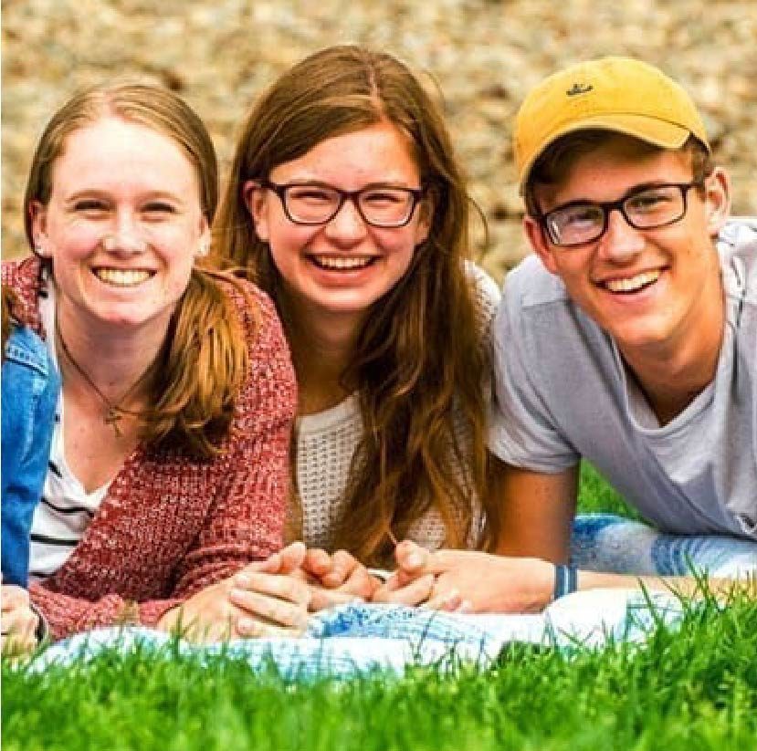 three students laying down on picnic blanket